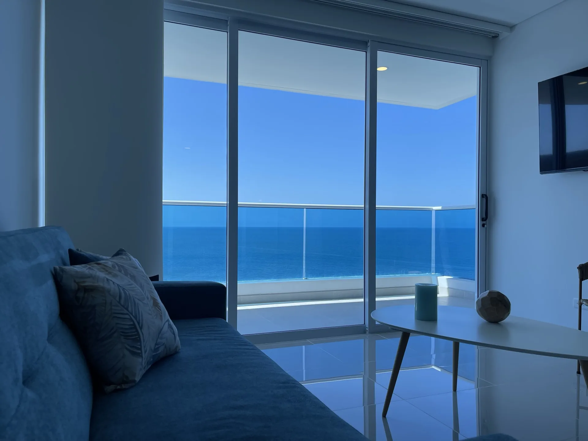 Sala con sofá azul y balcón panorámico al Mar Caribe